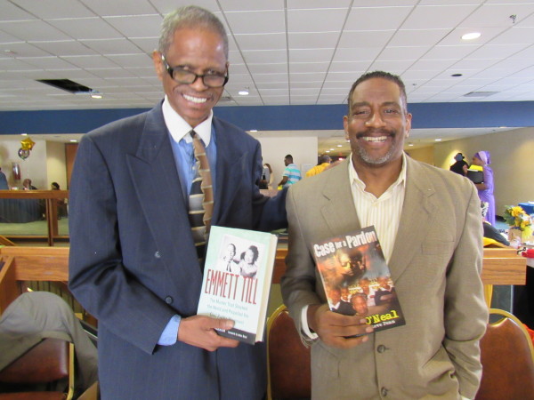 At the Harlem Book Fair Midwest today at the Reardon Civic Center in Kansas City, Kan., Alvin Sykes, left, holds a copy of a book, “Emmett Till, The Murder that Shocked the World and Propelled the Civil Rights Movement,” by Devery Anderson. Sykes’ efforts in reopening the Till case are mentioned in the book. At the right is former columnist Steve Penn, the author of the book, “Case for a Pardon,” about Pete O’Neal. 