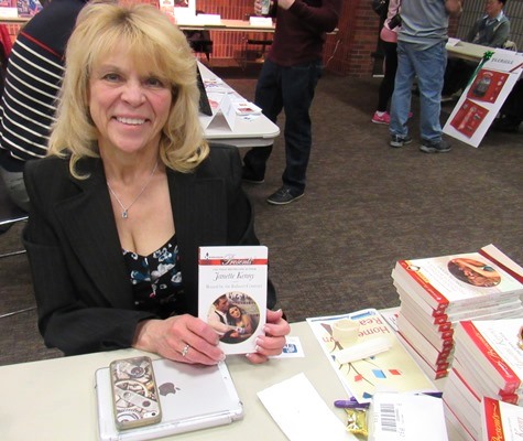 Bestselling romance author Janette Kenny held a copy of her book, “Bound by the Italian’s Contract,” on Saturday at the Homegrown Reads program at the West Wyandotte Library. (Photo by Mary Rupert)