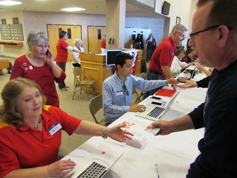 A voter wore his old Reagan for President sweatshirt as he showed his photo ID and checked into the Wyandotte County Republican caucus. Helping check in the voters was Tracy Ramey, left. (Staff photo)