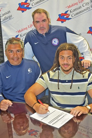 With head coach Ruben Rodriguez, left, and assistant Burke Slusher as witnesses, sophomore Jahren Barrow became the first Kansas City Kansas Community College soccer player to commit to an NCAA Division I college, Presbyterian College in Clinton, Mo. (KCKCC photo by Alan Hoskins)