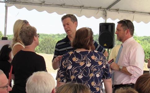 Before the groundbreaking, Gov. Sam Brownback visited with Mayor Mark Holland, right, and members of the Unified Government Commission. (Staff photo by Mary Rupert)