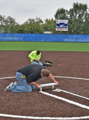 With a new scoreboard donated by the Precision Co. as a backdrop, the rubber on the pitching mound is finely tuned at KCKCC’s new softball complex. (KCKCC photo by Alan Hoskins)