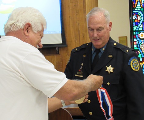 Stephen Barnhart prepared to bestow a medallion for volunteer service to Sheriff Don Ash at Thursday night's Unified Government Commission meeting. (Staff photo by Mary Rupert)