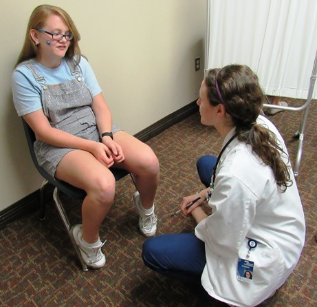 Emalee Patterson, right, a second-year medical student, provided a sports physical today at the Back-to-School Fair at Kansas City Kansas Community College. She was volunteering through the University of Kansas Medical Center Family Medicine Research Division.  (Staff photo)