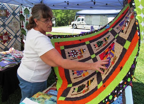 Mary Beth Pace, Shawnee, displayed some one-of-a-kind quilts she made during the Grinter Summerfest Saturday at 78th and K-32. This particular quilt had 39 pieces in one quilt block, she said.  Many of her quilts are from reproduction fabrics. She is a native of Wyandotte County.   The  free Grinter Summerfest continues until 4 p.m. Saturday. (Staff photo)