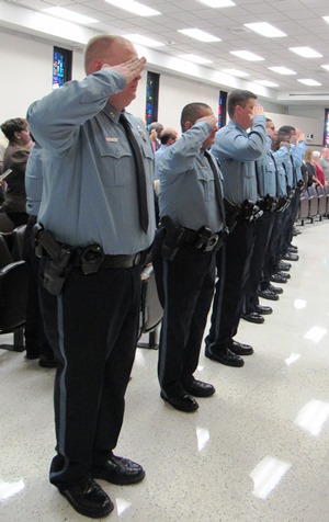 Nine new police officers saluted the flag during graduation ceremonies Thursday night at Kansas City, Kan., City Hall. (Staff photo)