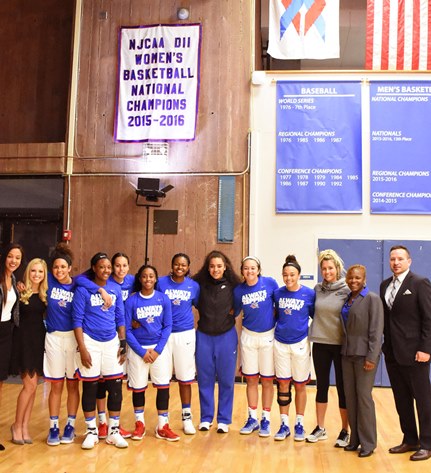 The 2016 NJCAA Division II national championship banner was unveiled in the KCKCC Field House Saturday by members of the 2015-2016 team, from left, assistant coach Chamissa Anderson, Brooklyn Bockover, Brooklyn Wagler, Ky’Ana French, Millie Shade, Valencia Scott, Kyliea Jarrett, Nimo Samana, Brie Tauai, Whitney Hazlett, Janay Jacobs, assistant coach Dawn Adams and head coach Joe McKinstry. (KCKCC photo by Alan Hoskins) 